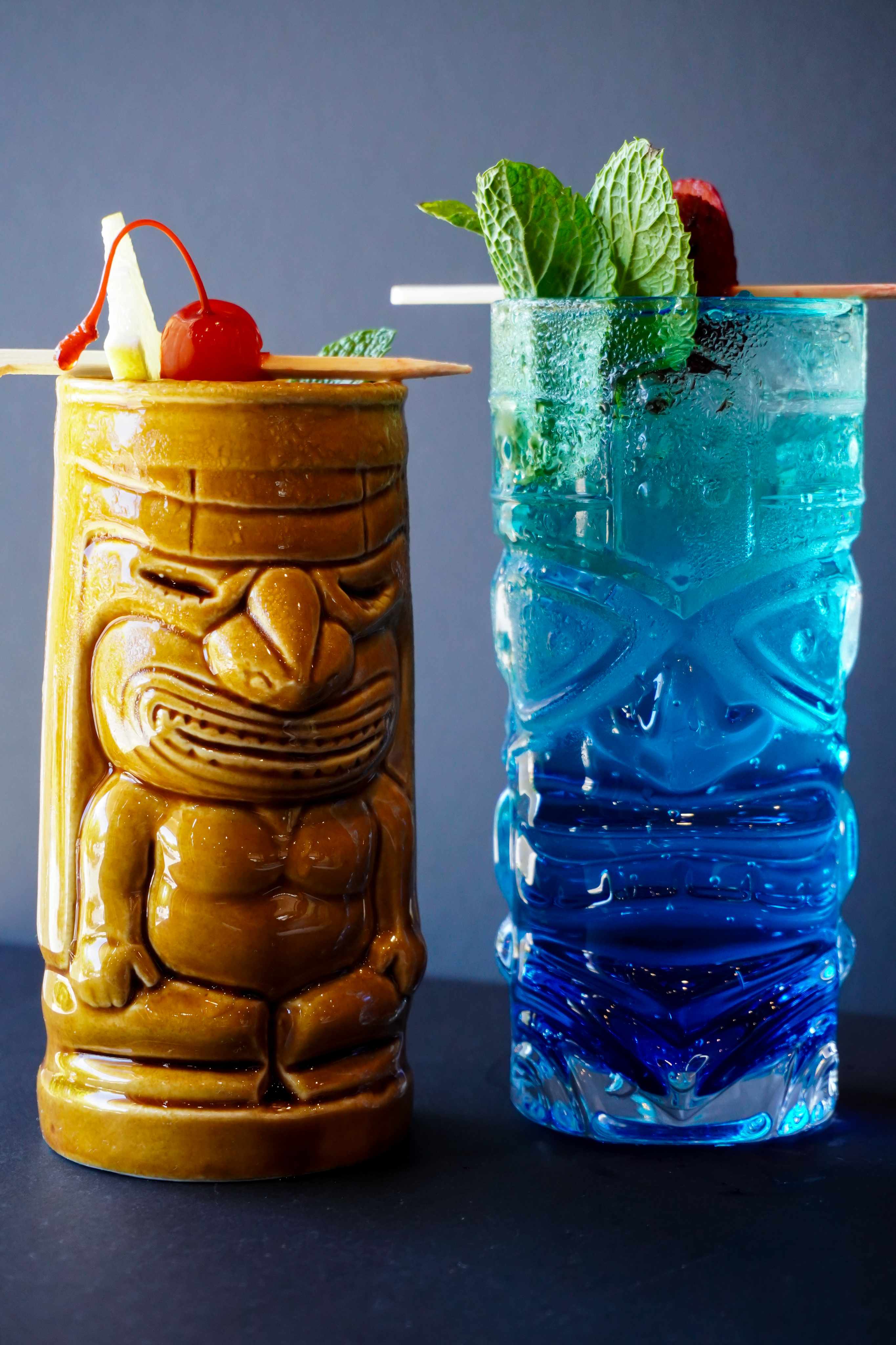 PLACEHOLDER — Cocktail - 4.png: tiki mug beside an icy blue highball with mint